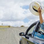 a passenger holding a hat outside the window of a car while having a roadtrip